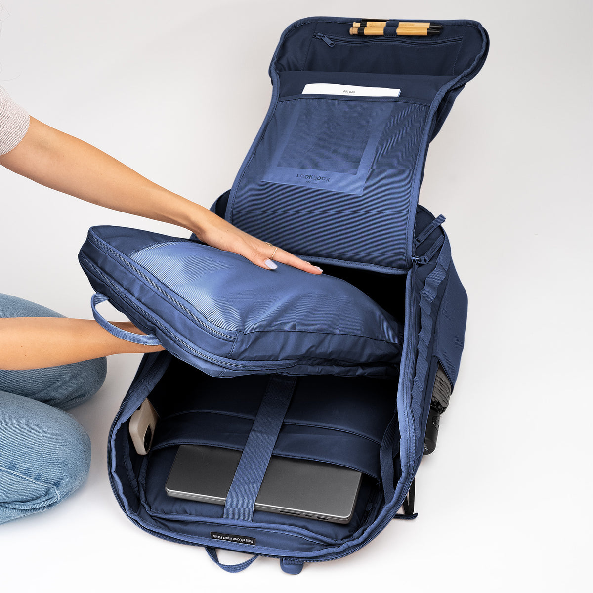 Eine Frau legt ein separates Fach in einen geöffneten PRO PACK TRAVEL Rucksack.