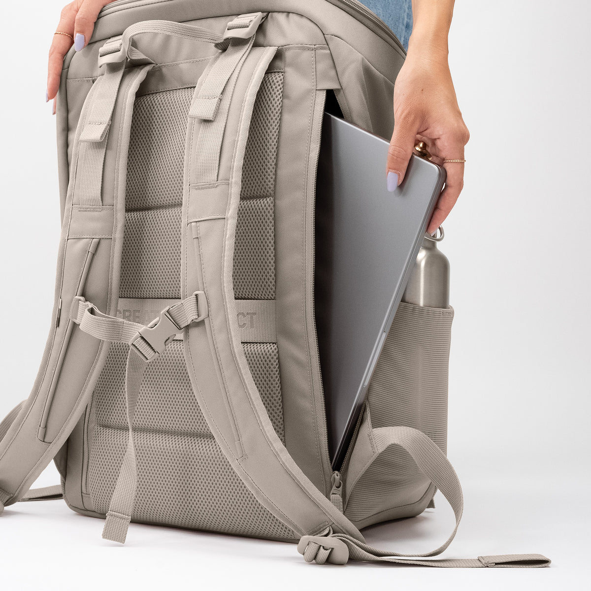 PRO PACK TRAVEL Rucksack in scallop (helles Beige), eine Frau steckt einen Laptop in das Seitenfach.