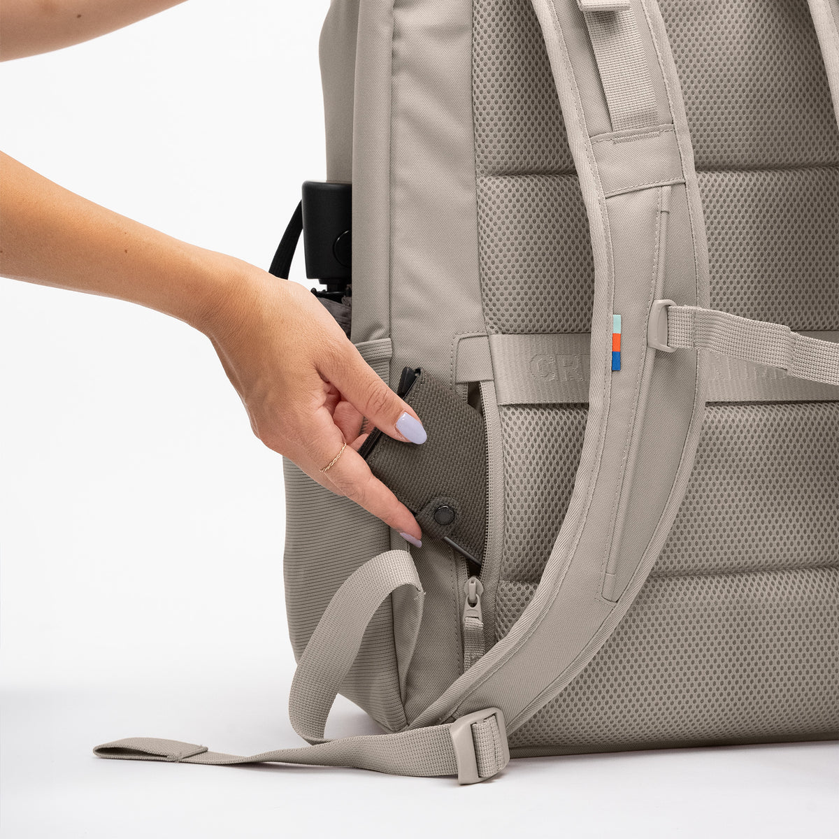 PRO PACK TRAVEL Rucksack in scallop (helles Beige), Hand einer Frau greift in die Seitentasche.