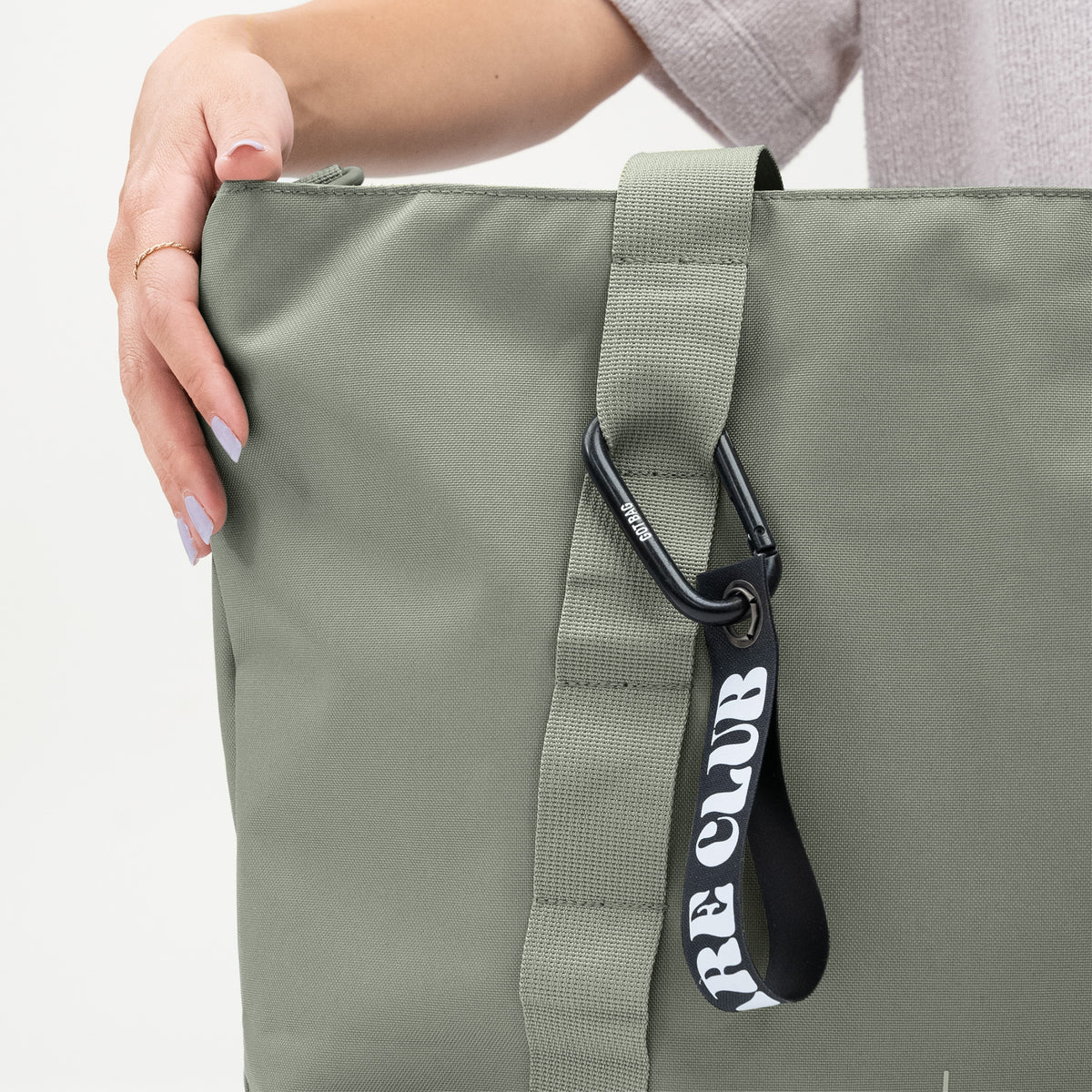 TOTE BAG Tasche in bass (Salbeigrün) von einer Frau in der Hand gehalten.
