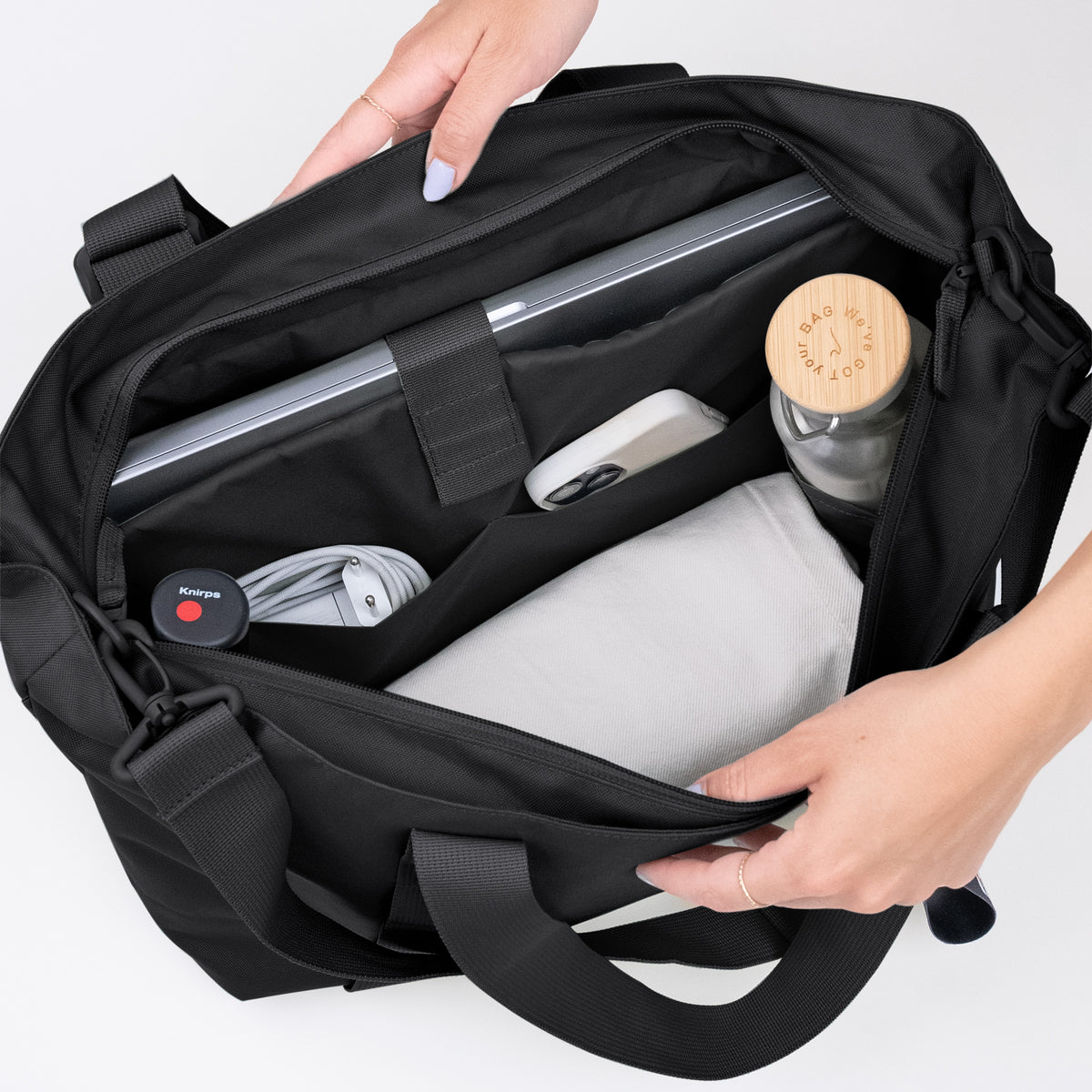 TOTE BAG Tasche in black (Schwarz) von einer Frau geöffnet, mit Laptop, Handy und Flasche.