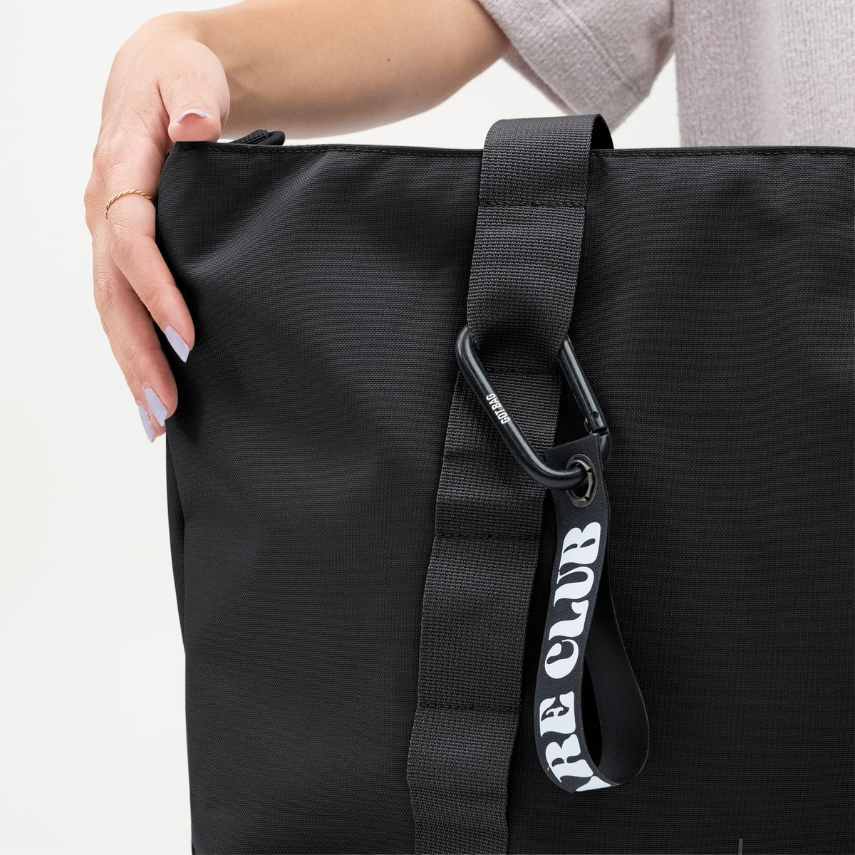 TOTE BAG Tasche in black (Schwarz) von einer Frau in der Hand gehalten.