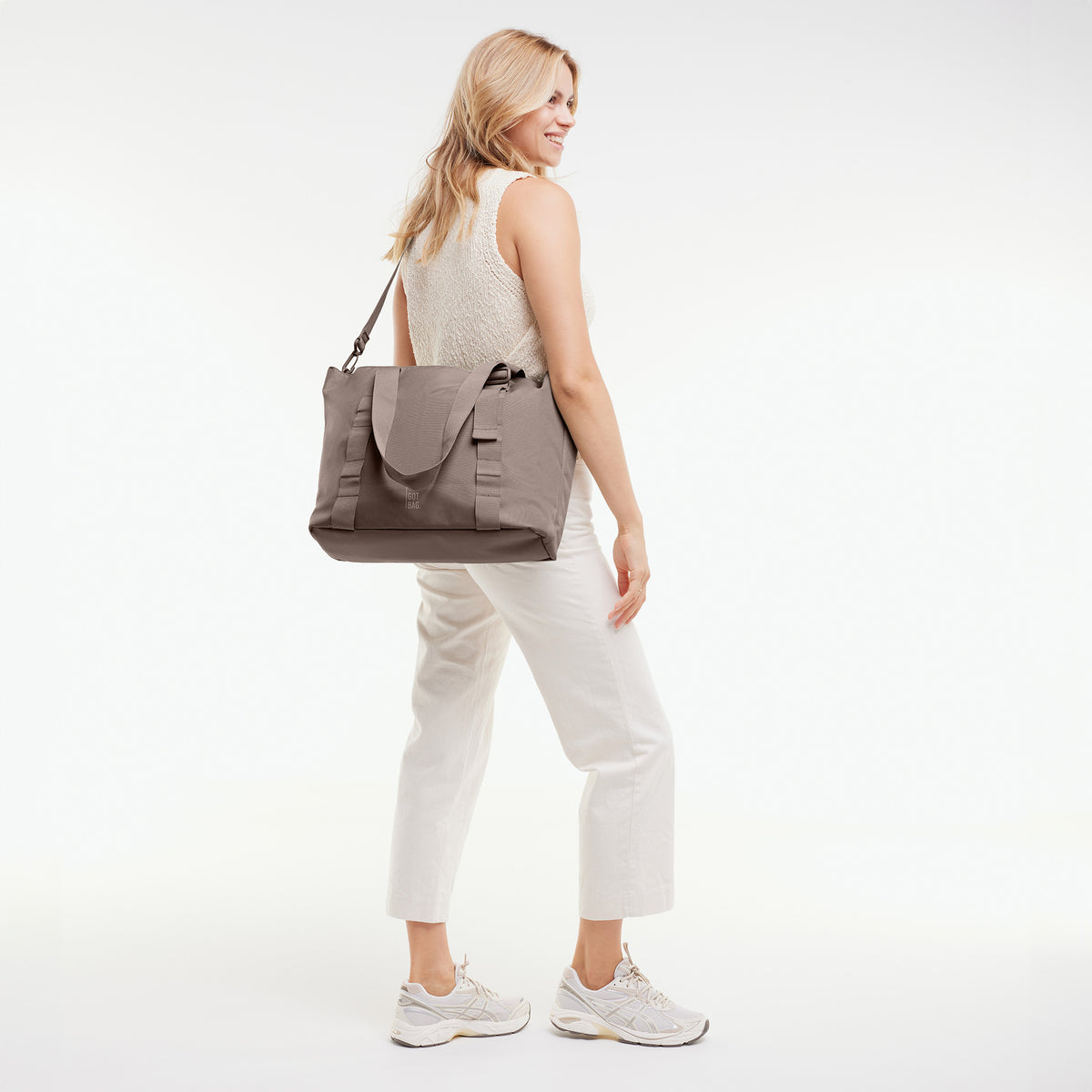 TOTE BAG Tasche in oyster (klassisches Taupe-Braun) von einer Frau über der Schulter getragen.