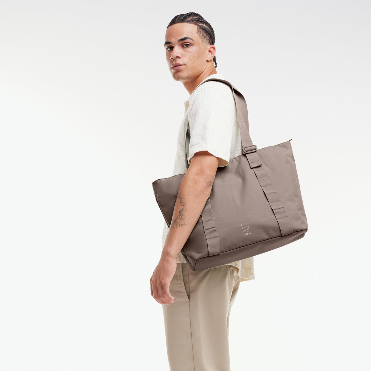 TOTE BAG Tasche in oyster (klassisches Taupe-Braun) von einem Mann über der Schulter getragen.