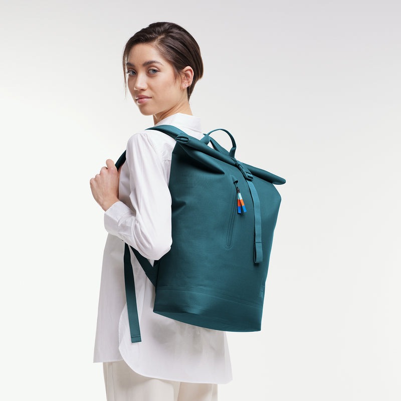 ROLLTOP LITE 2.0 Rucksack in cliff (dunkles Petrol) von einer Frau als Rucksack auf dem Rücken getragen.