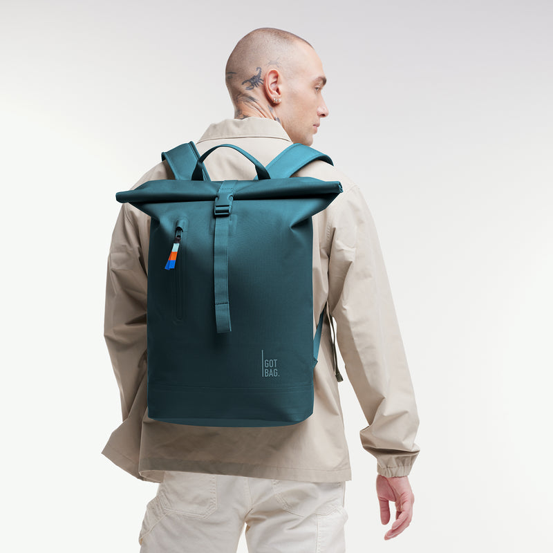ROLLTOP LITE Rucksack in cliff (dunkles Petrol) von einem Mann auf dem Rücken getragen.