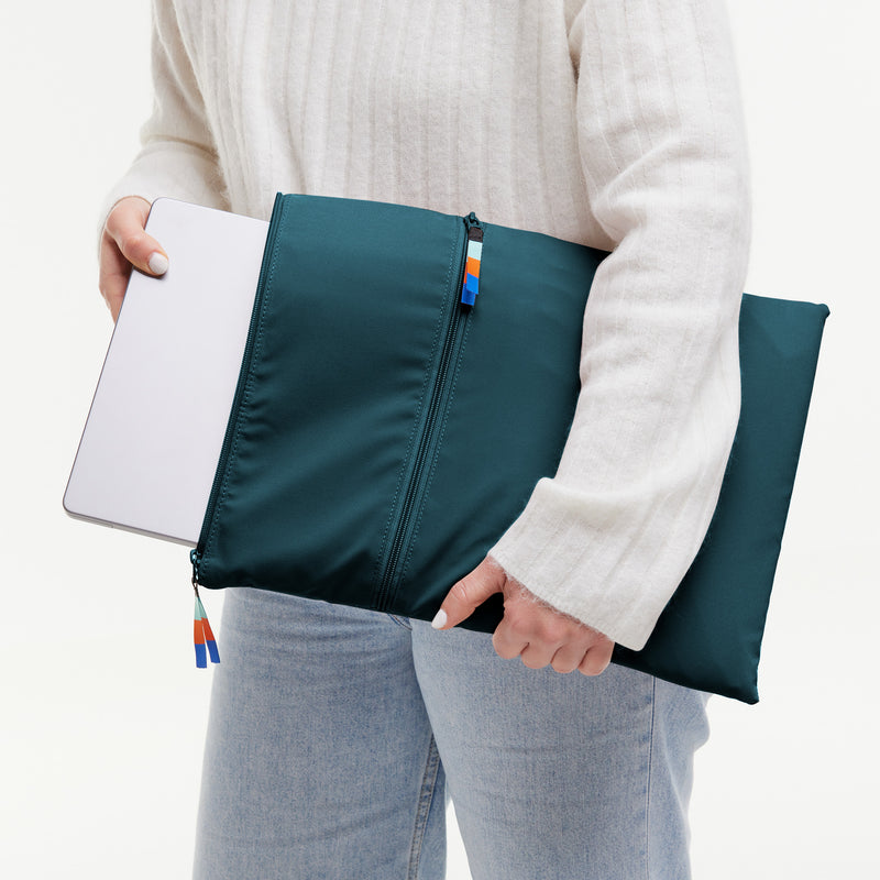 ROLLTOP LITE Accessoire in cliff (dunkles Petrol), von einer Frau, die einen Laptop einsteckt.