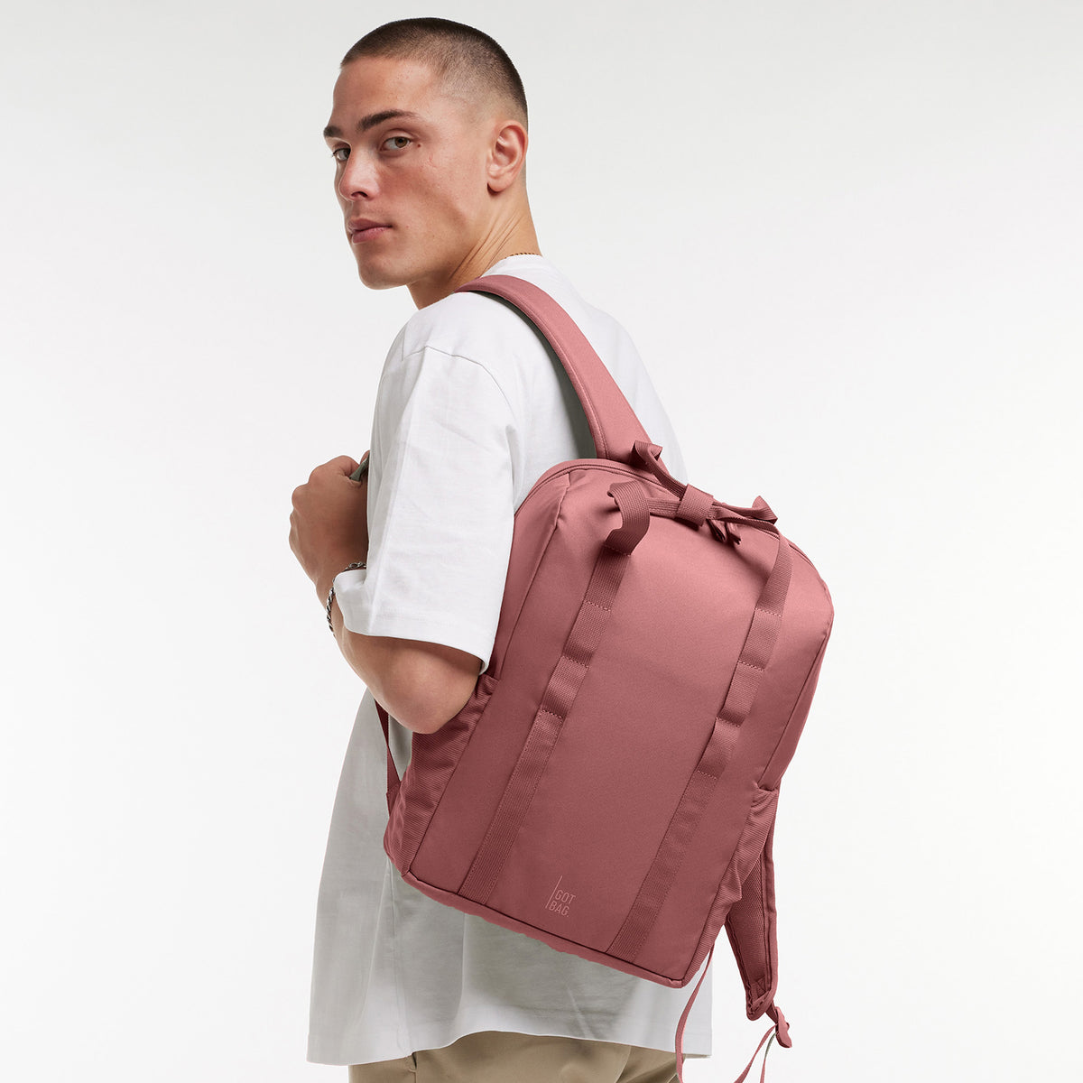 DAYPACK LOOP Rucksack in lionfish (dunkles Rosa mit Rotstich) von einem Mann auf dem Rücken getragen.