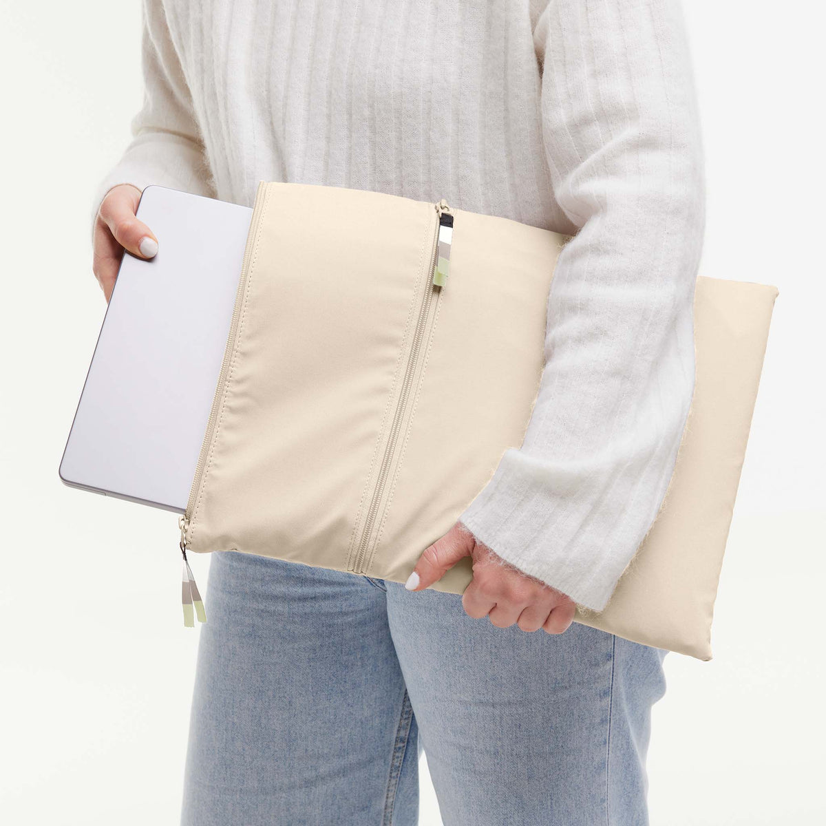 ROLLTOP Tasche in salt (warmes Cremeweiß) von einer Frau in den Händen gehalten, die einen Laptop hineinsteckt.