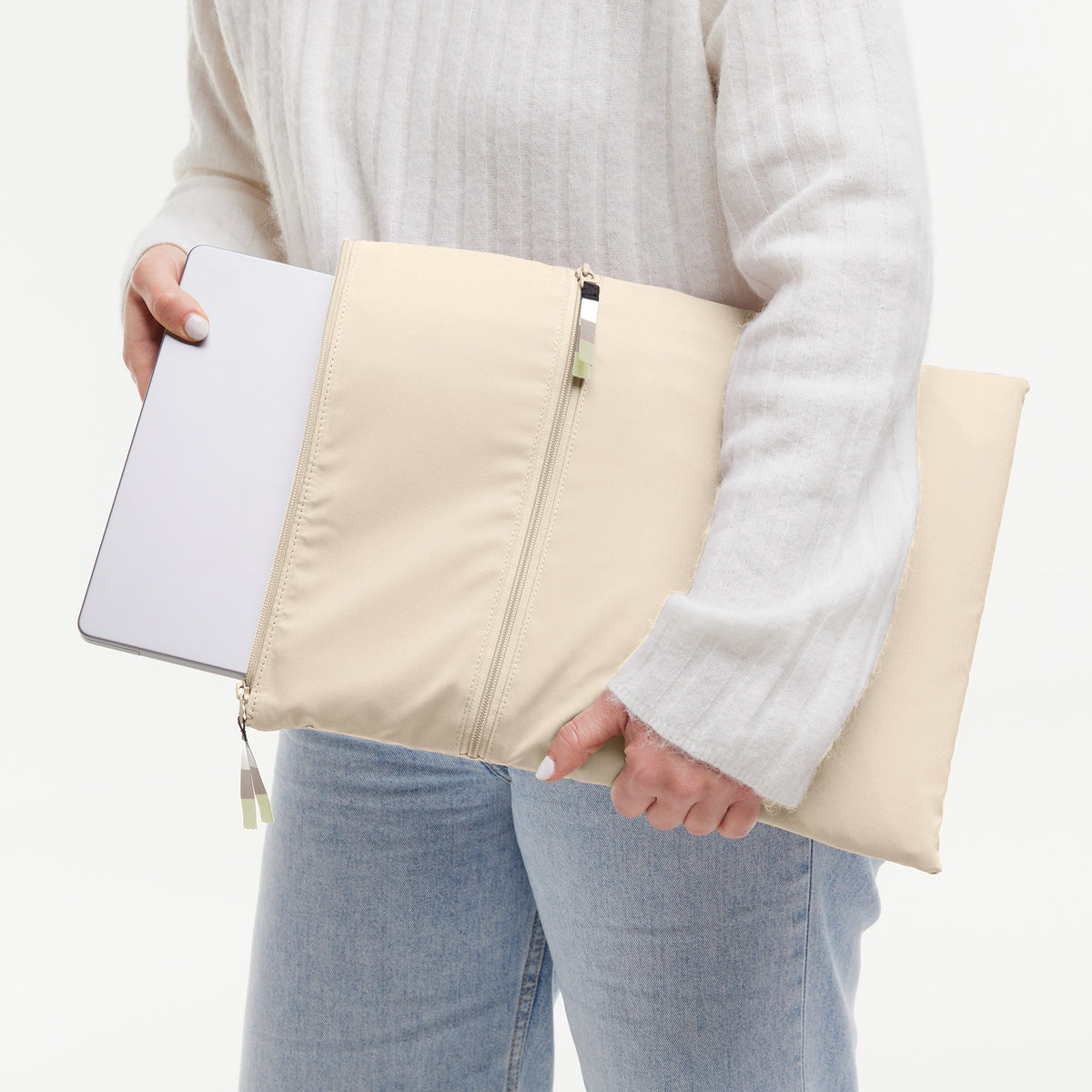 ROLLTOP LITE Tasche in salt (warmes Cremeweiß), von einer Frau in Jeans und weißem Pullover gehalten, die einen Laptop hineinsteckt.