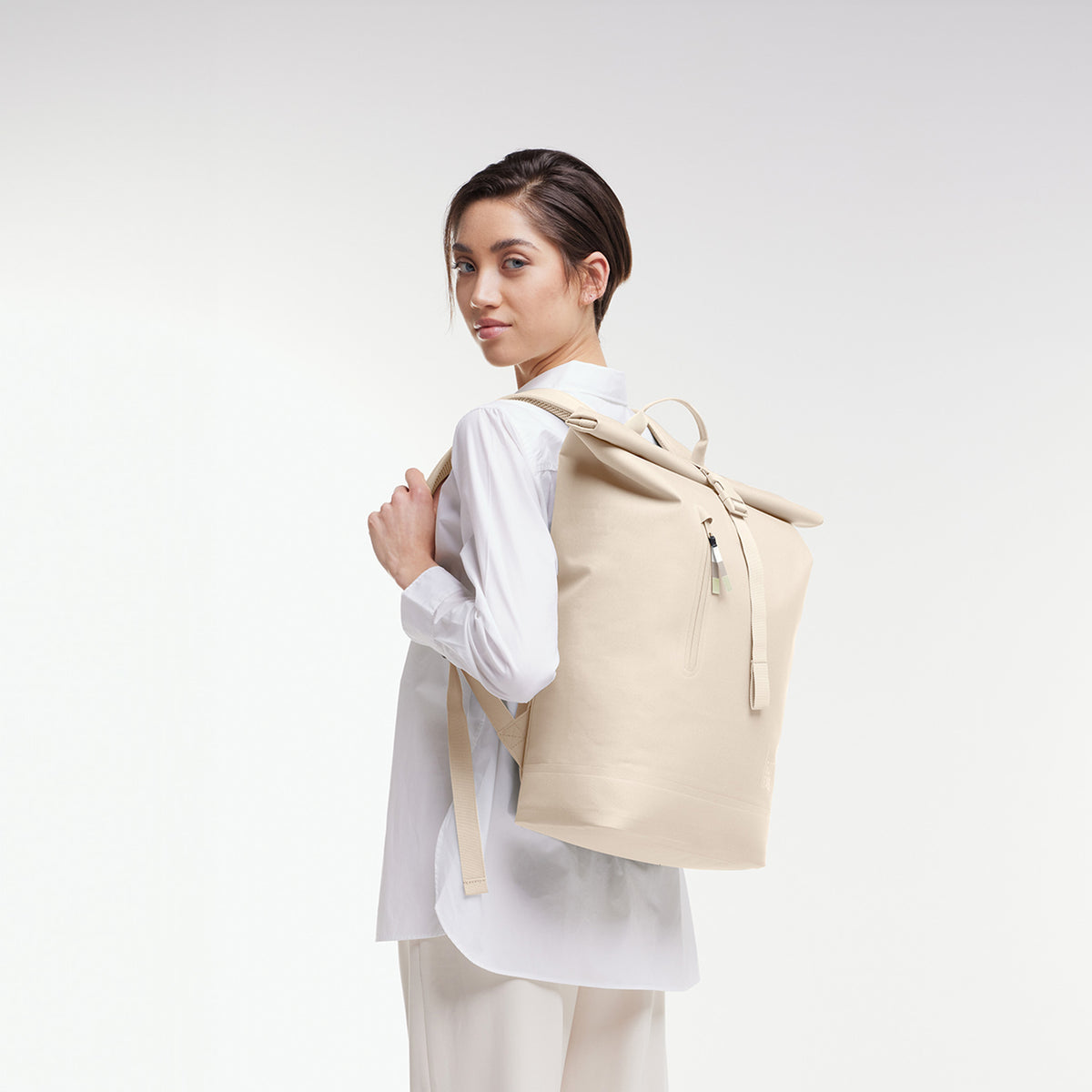 ROLLTOP LITE Rucksack in salt (warmes Cremeweiß) von einer Frau als Rucksack auf dem Rücken getragen.