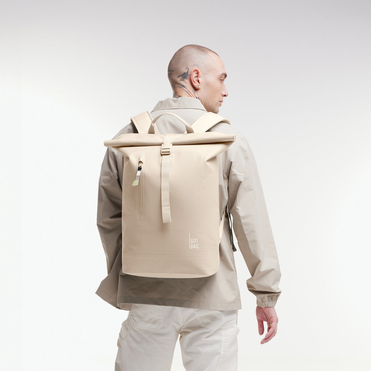 ROLLTOP LITE Rucksack in salt (warmes Cremeweiß) von einem Mann als Rucksack auf dem Rücken getragen.