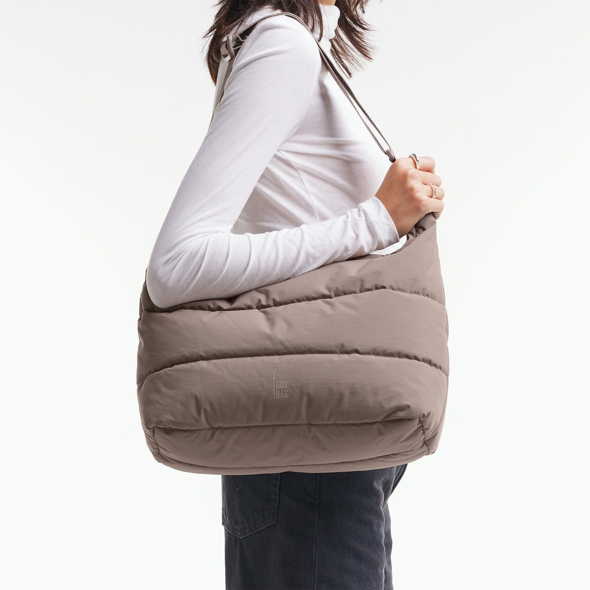 PUFFER SQUARE BAG Tasche in oyster (klassisches Taupe-Braun) von einer Frau über der Schulter getragen.