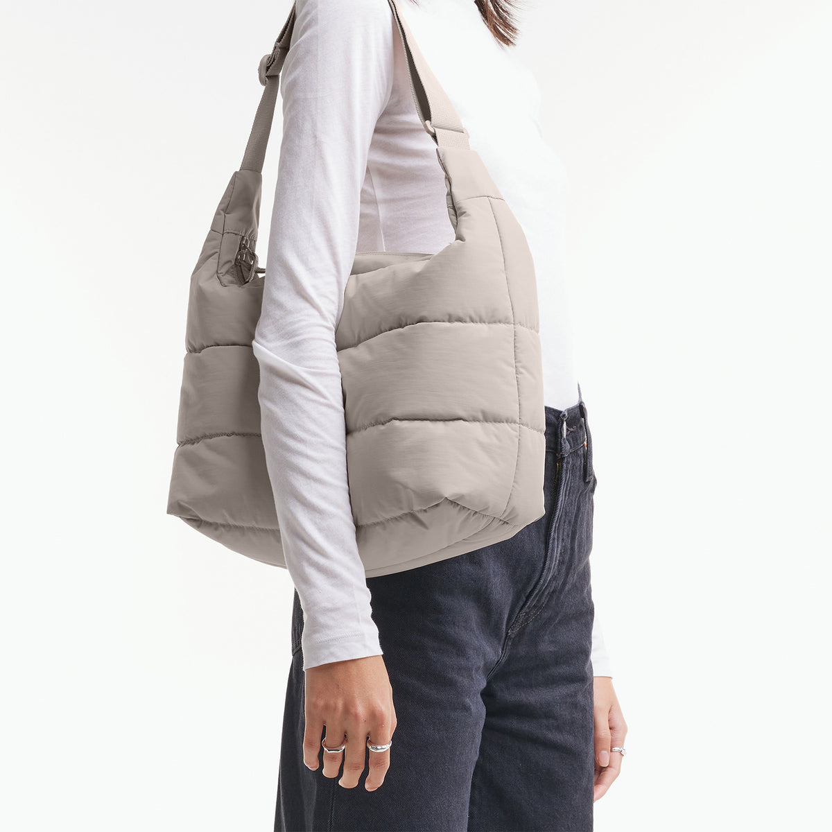 PUFFER SQUARE BAG Tasche in scallop (helles Beige) von einer Frau über der Schulter getragen.
