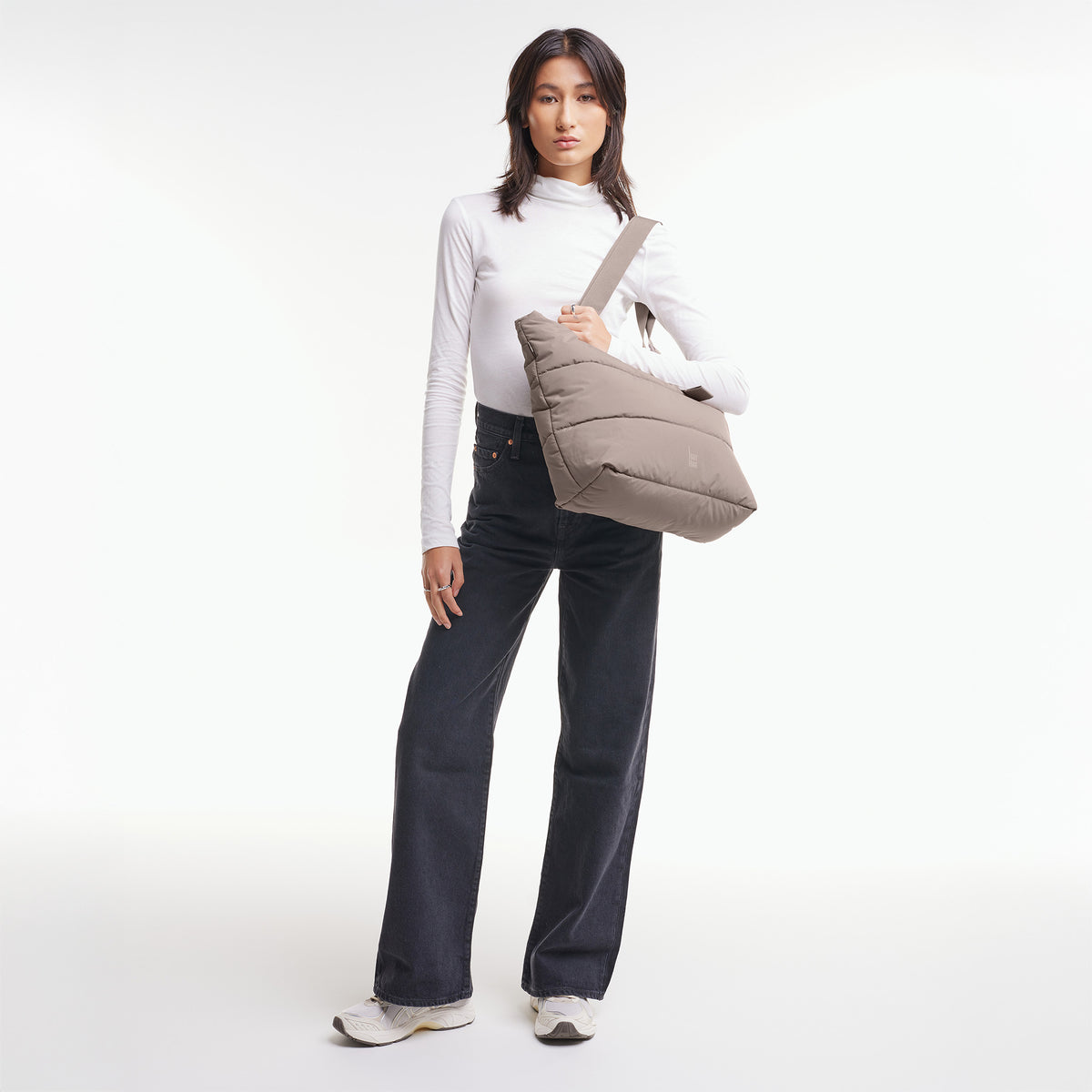 PUFFER TOTE BAG Tasche in oyster (klassisches Taupe-Braun) von einer Frau über der Schulter getragen.