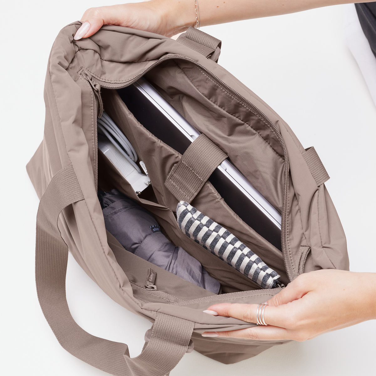 PUFFER TOTE BAG Tasche in oyster (klassisches Taupe-Braun), von einer Frau gehalten, zeigt das Innere mit Laptop.
