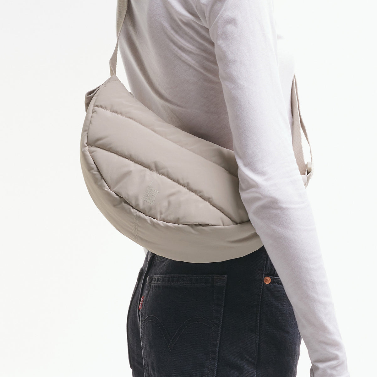 PUFFER MOON BAG SMALL Tasche in scallop (helles Beige) von einer Frau crossbody getragen.