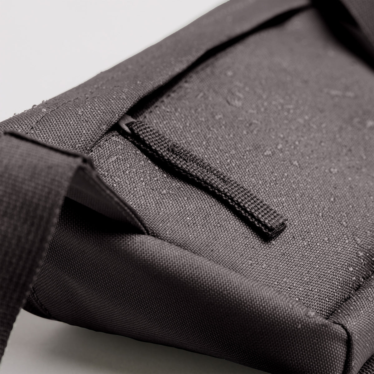 HIP BAG Tasche in mussel (dunkles Braun-Grau) als Detailaufnahme mit Wassertropfen auf dem Stoff.
