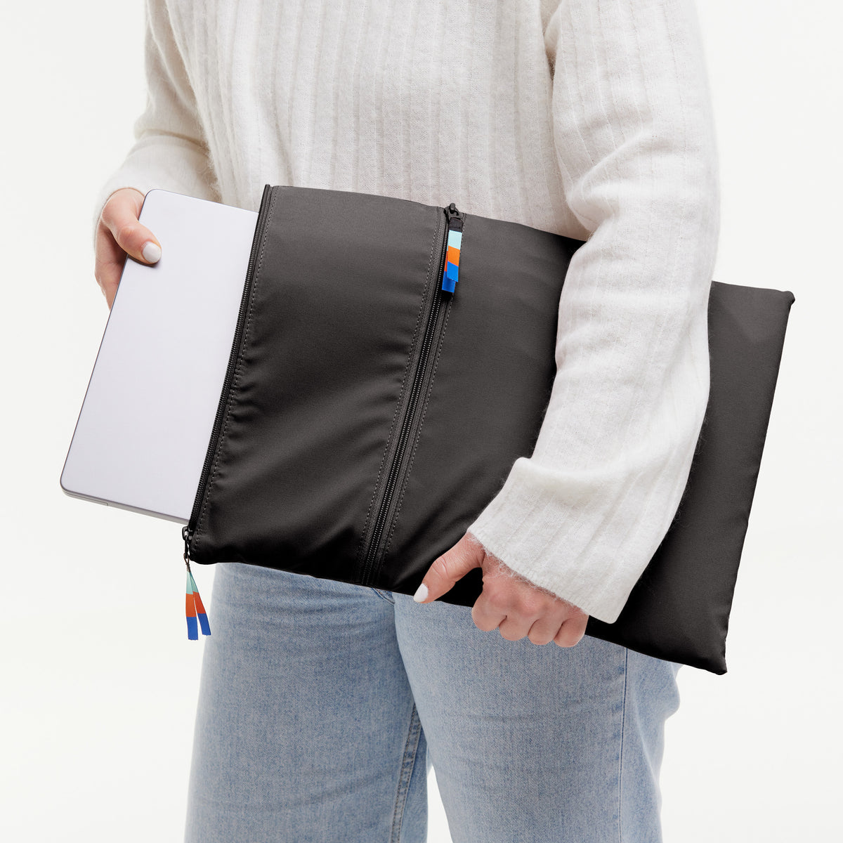ROLLTOP LITE Tasche in mussel (dunkles Braun-Grau), von einer Frau gehalten, die einen Laptop hineinsteckt.