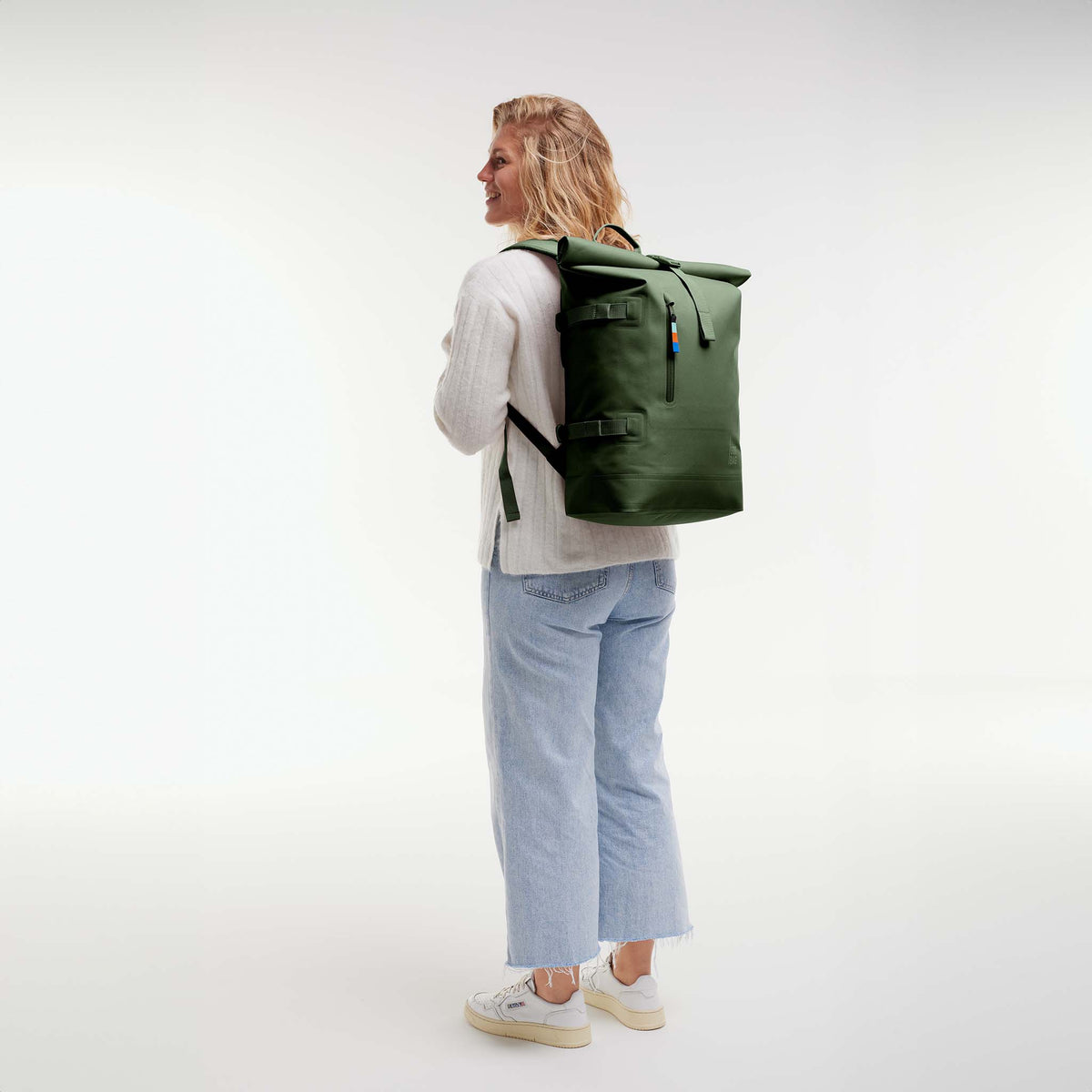 ROLLTOP 2.0 Rucksack in seafloor (tiefes Dunkelgrün) von einer Frau als Rucksack auf dem Rücken getragen.