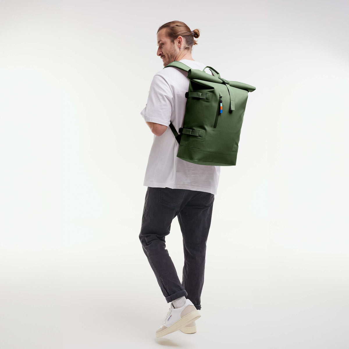 ROLLTOP Rucksack in seafloor (tiefes Dunkelgrün) von einem Mann auf dem Rücken getragen.