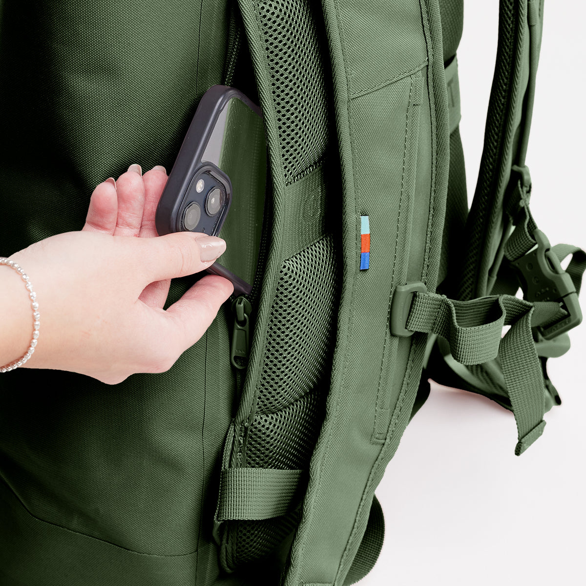 ROLLTOP LITE 2.0 Rucksack in seafloor (tiefes Dunkelgrün), eine Frau steckt Smartphone in Netztasche.