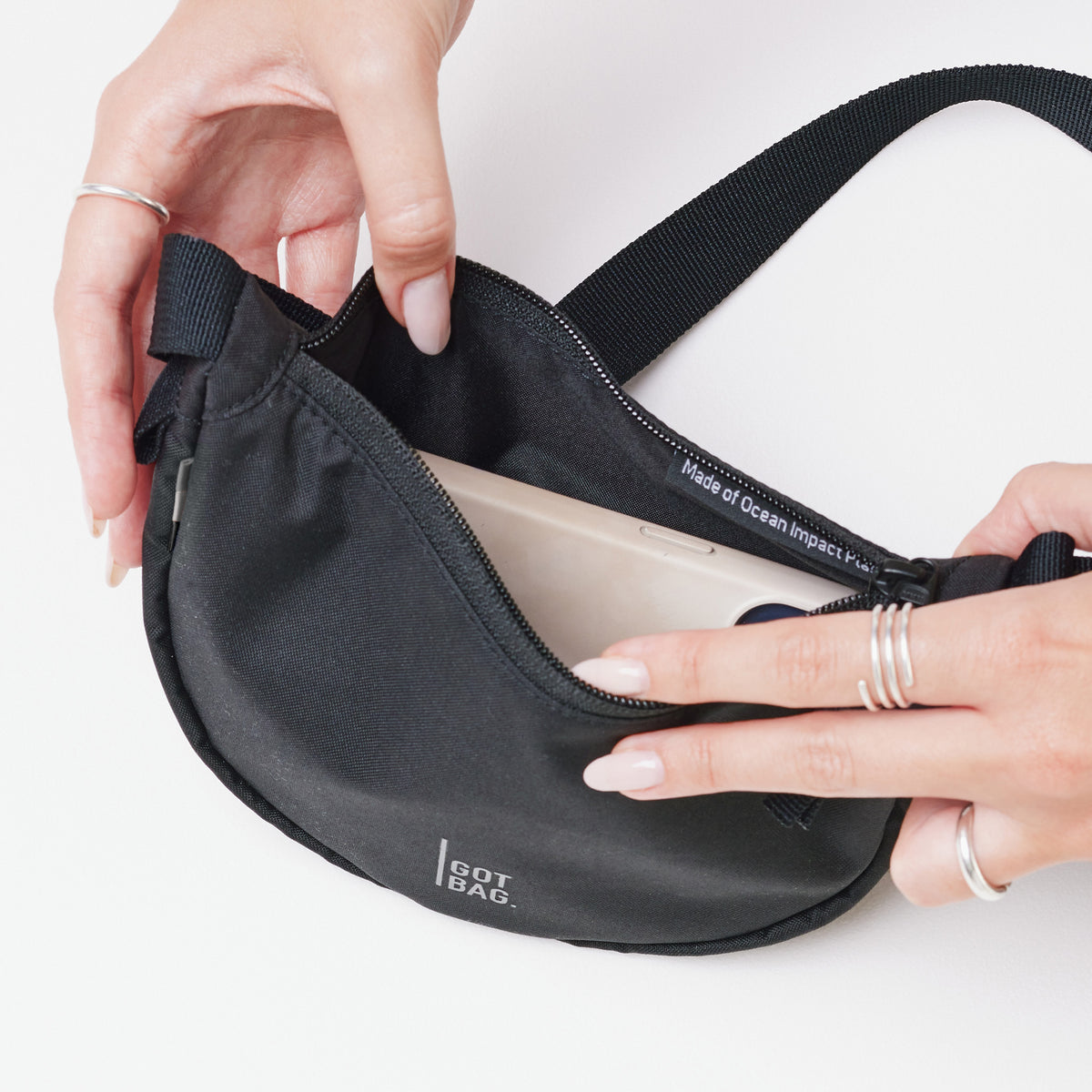 MOON BAG MINI Tasche in black (Schwarz) von einer Frau in den Händen gehalten und geöffnet.