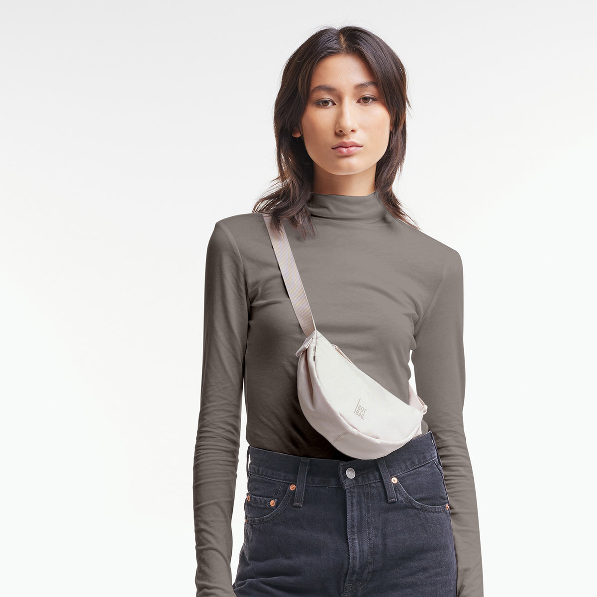 MOON BAG MINI Tasche in soft shell (warmes Cremeweiß) von einer Frau crossbody getragen.