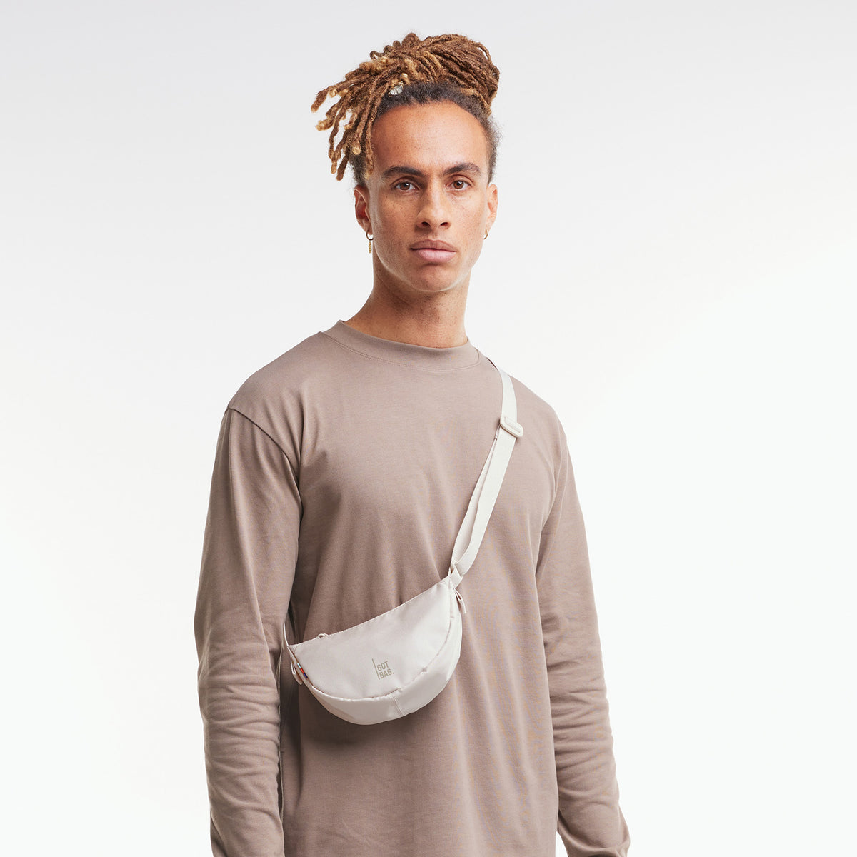 MOON BAG MINI Tasche in soft shell (warmes Cremeweiß) von einem Mann crossbody getragen.