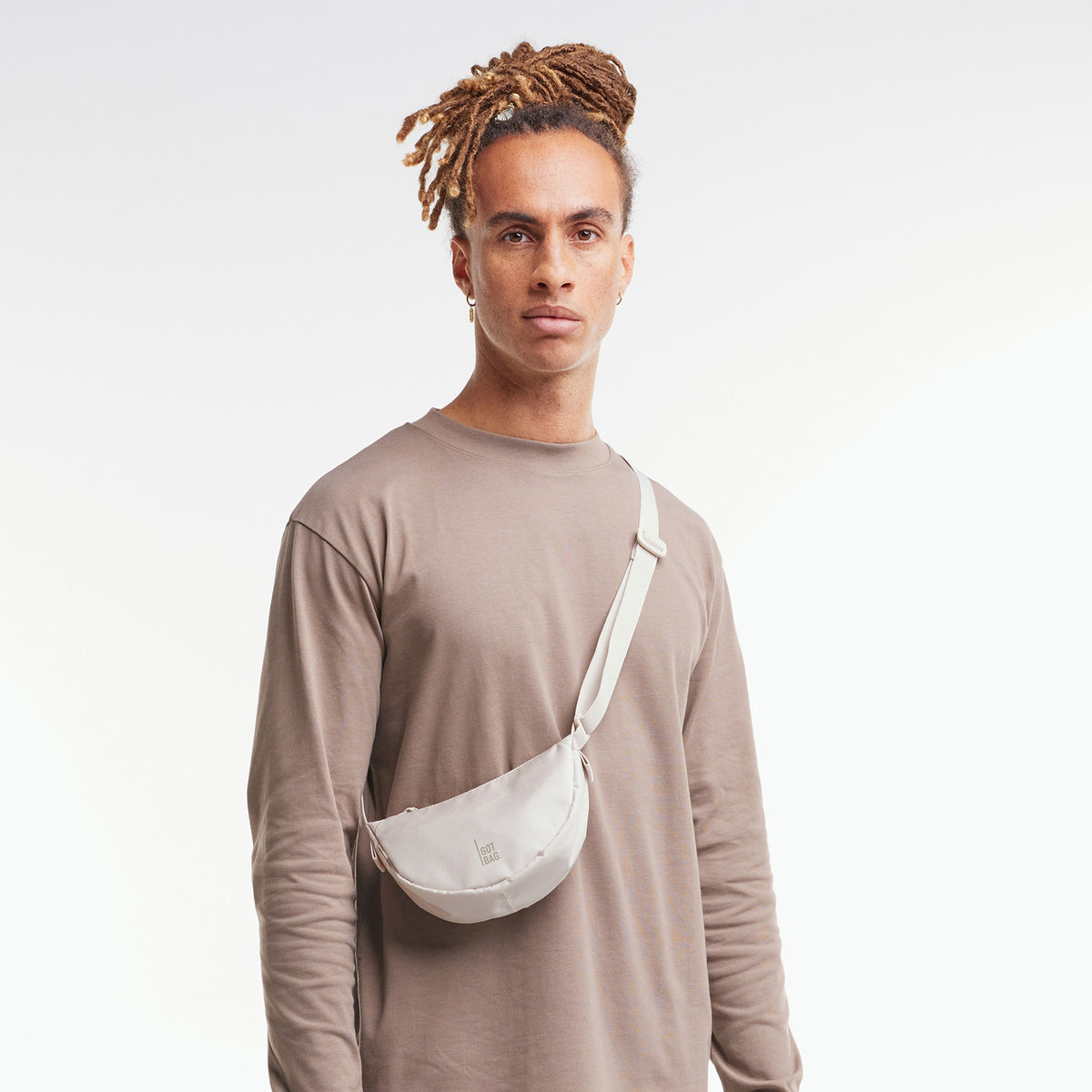 MOON BAG MINI Tasche in soft shell (warmes Cremeweiß) von einem Mann crossbody getragen.