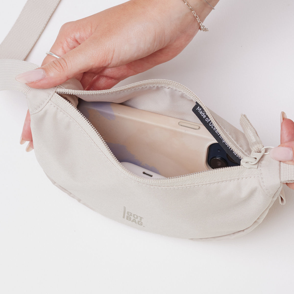 MOON BAG MINI Tasche in soft shell (warmes Cremeweiß) von einer Frau geöffnet.