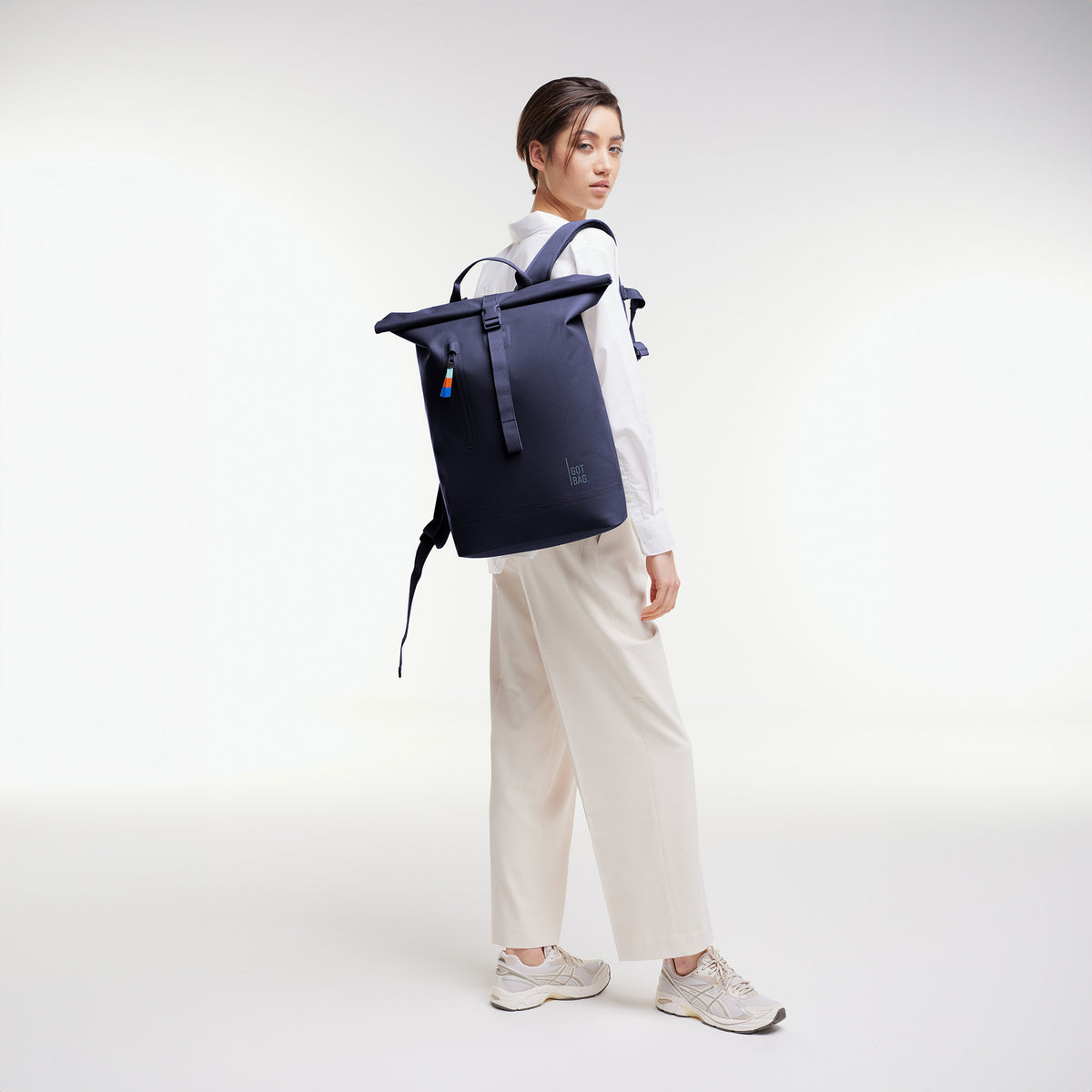ROLLTOP LITE 2.0 Rucksack in tide (tiefes Dunkelblau mit Lilastich) von einer Frau auf dem Rücken getragen.