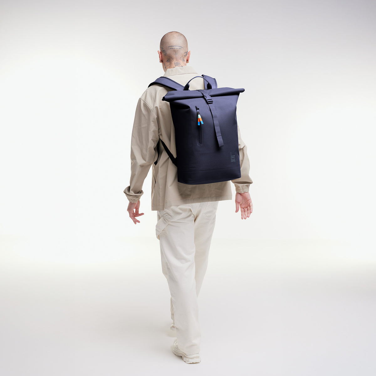 ROLLTOP LITE 2.0 Rucksack in tide (tiefes Dunkelblau mit Lilastich) von einem Mann auf dem Rücken getragen.