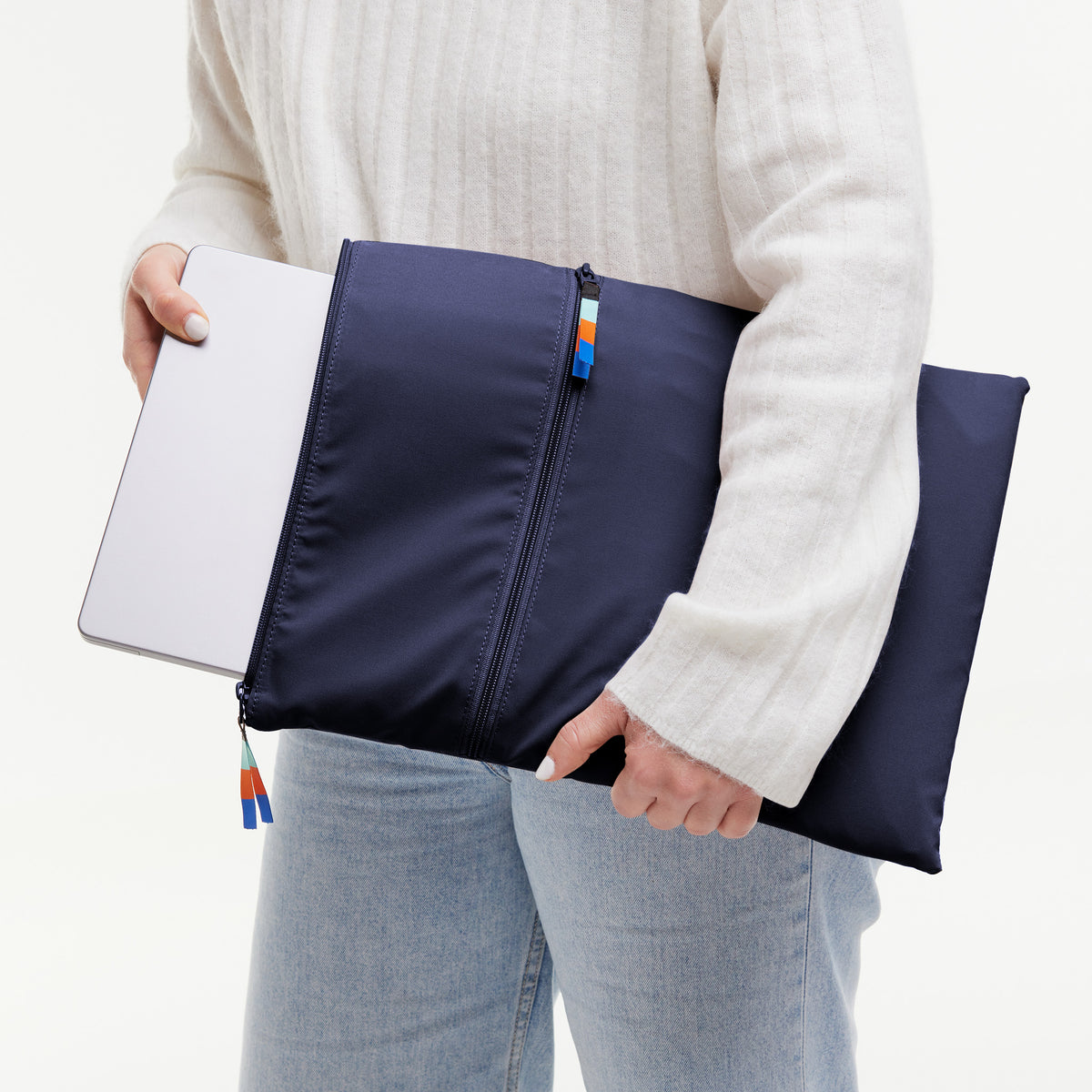 ROLLTOP LITE Accessoire in tide (tiefes Dunkelblau mit Lilastich), von einer Frau gehalten, die einen Laptop hineinsteckt.