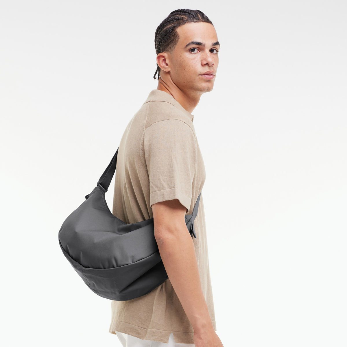 MOON BAG LARGE Tasche in shark (Dunkelgrau) von einem Mann über der Schulter getragen.