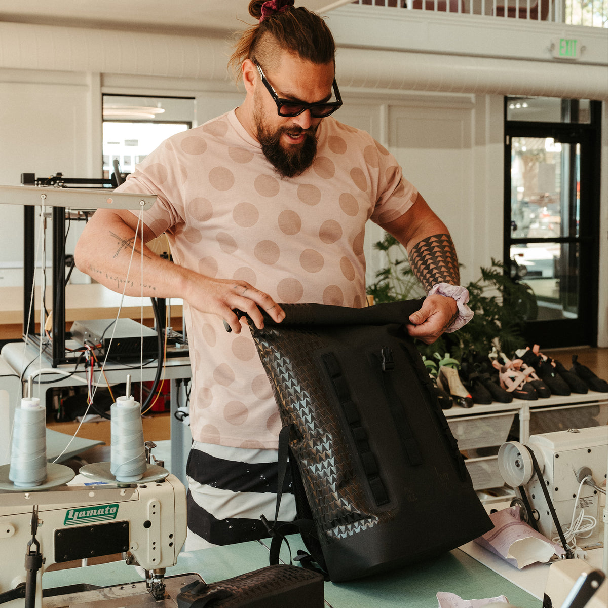 ROLLTOP ON THE ROAM Rucksack in black (Schwarz) von einem Mann in den Händen gehalten und oben verschlossen.
