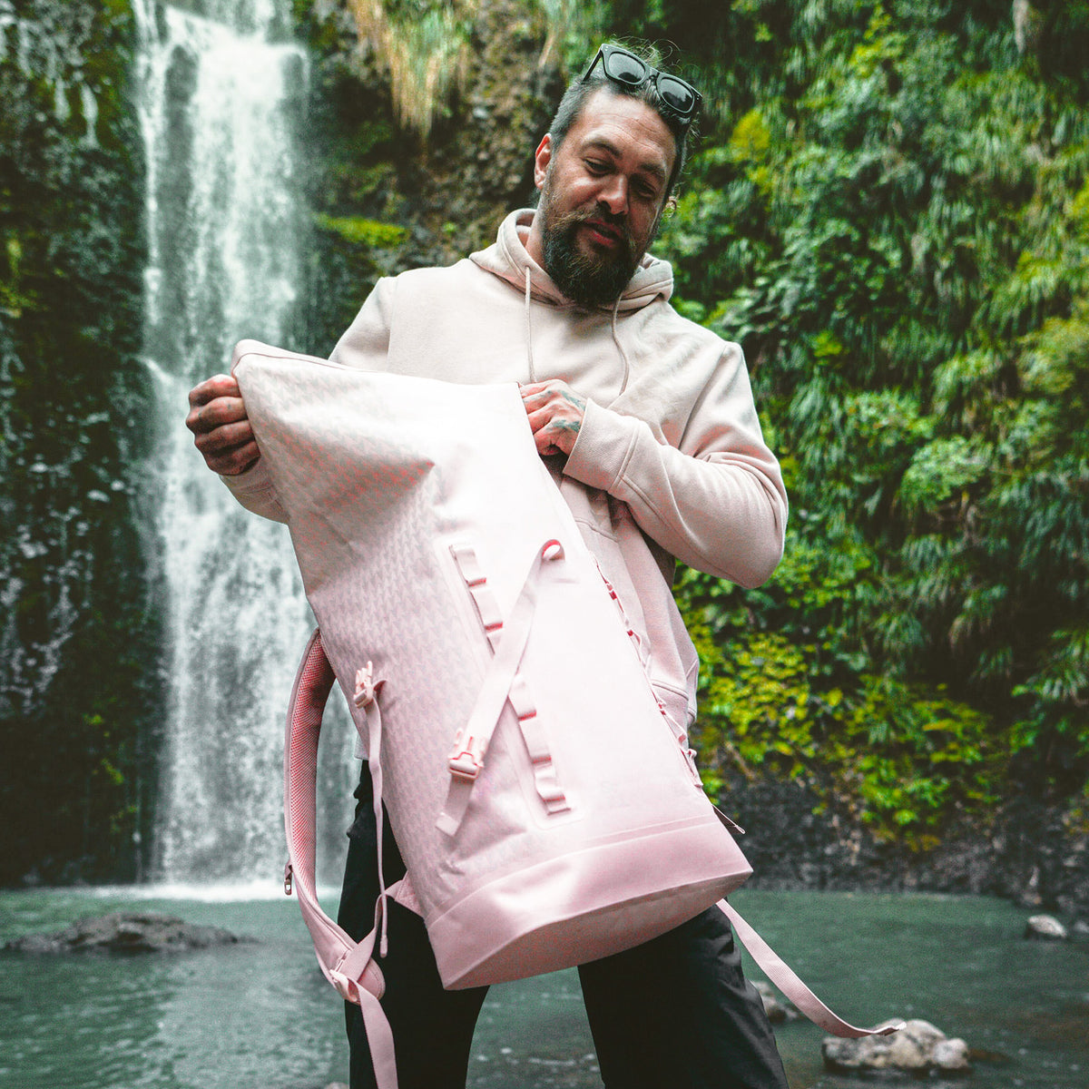 ROLLTOP ON THE ROAM Rucksack in dirty pink, von einem Mann gehalten und geöffnet.