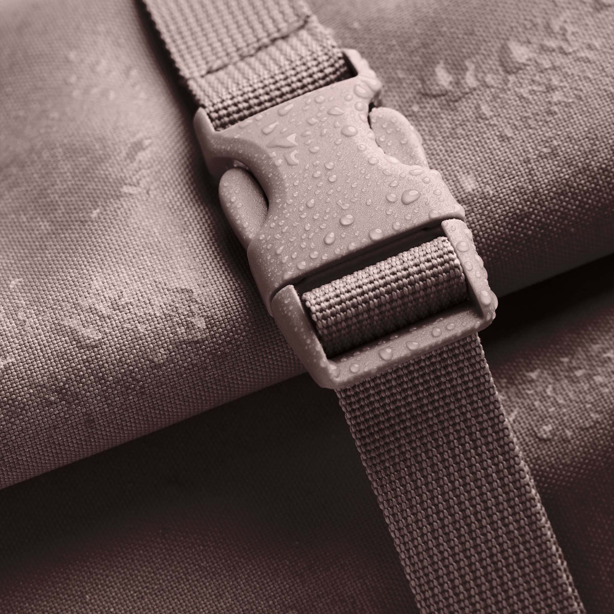 ROLLTOP 2.0 MONOCHROME EDITION Rucksack in blobfish (dunkles Altrosa) als Detailaufnahme einer Schnalle mit Wassertropfen.