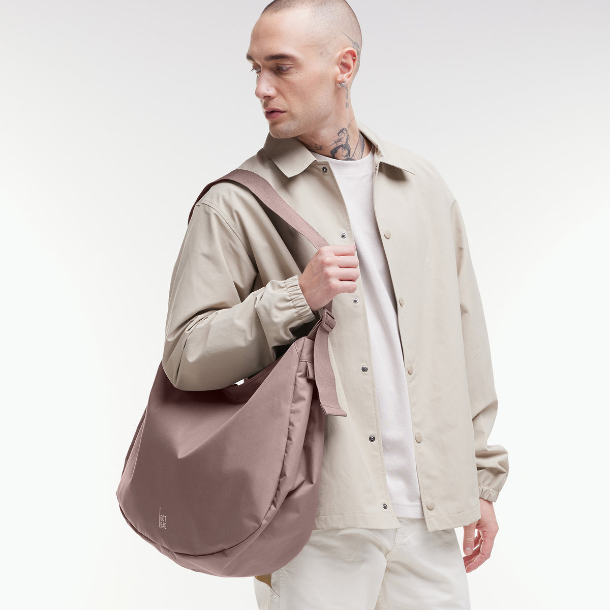 CURVED BAG Tasche in blobfish (dunkles Altrosa) von einem Mann über der Schulter getragen.