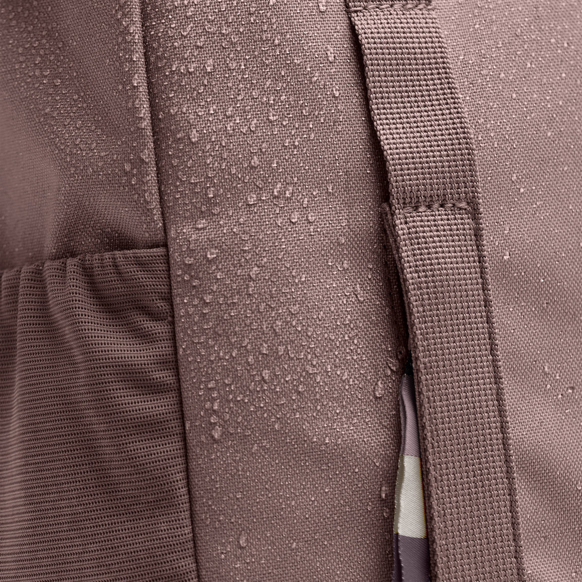 DAYPACK LOOP Rucksack, Detailaufnahme des wasserabweisenden Materials mit Wassertropfen und Gurt.