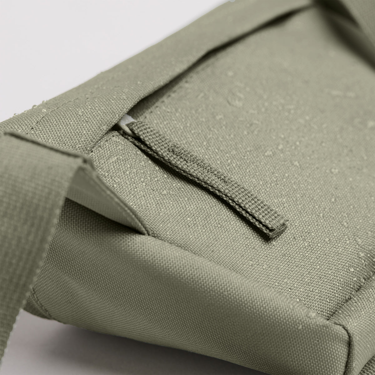 HIP BAG Tasche in seabed (helles Olivgrün) als Detailaufnahme des wasserabweisenden Materials mit Wassertropfen.