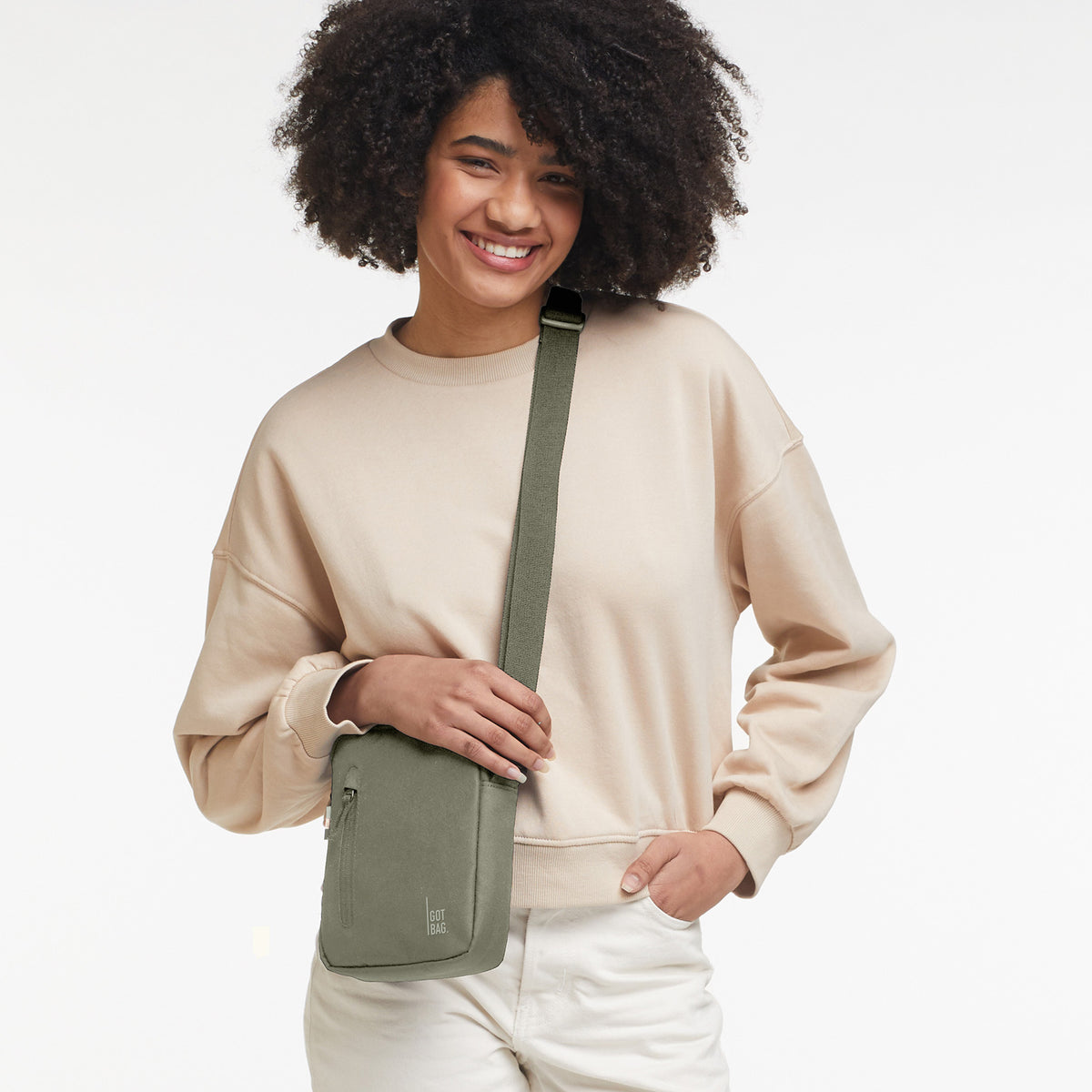 PUSHER BAG Tasche in seabed (helles Olivgrün) von einer Frau crossbody getragen.