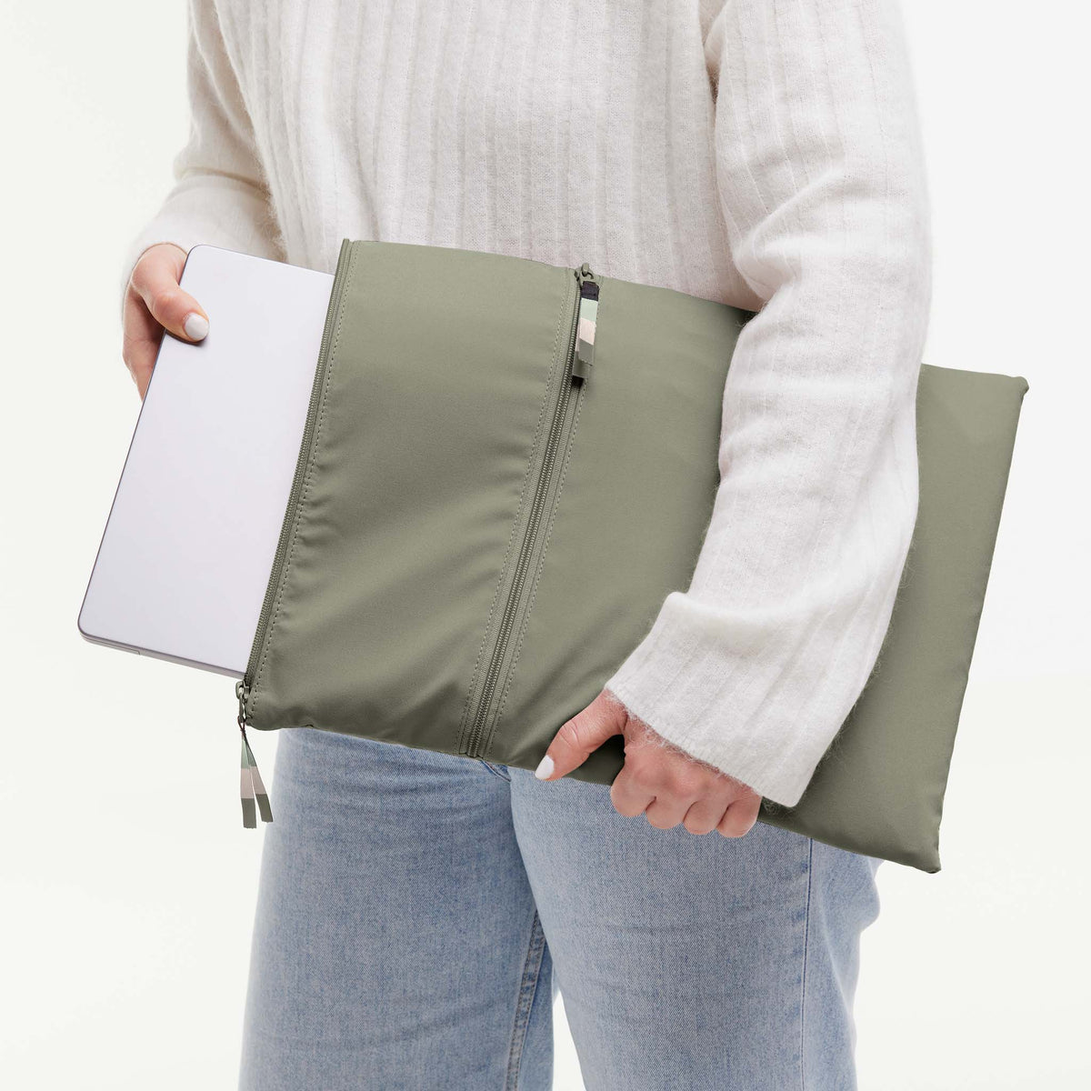 ROLLTOP Tasche in seabed (helles Olivgrün) von einer Frau gehalten, die einen silbernen Laptop hineinschiebt.