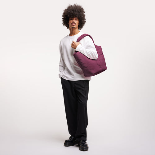 CLOUD TOTE BAG Tasche in kraken (Weinrot) von einem Mann über der Schulter getragen.