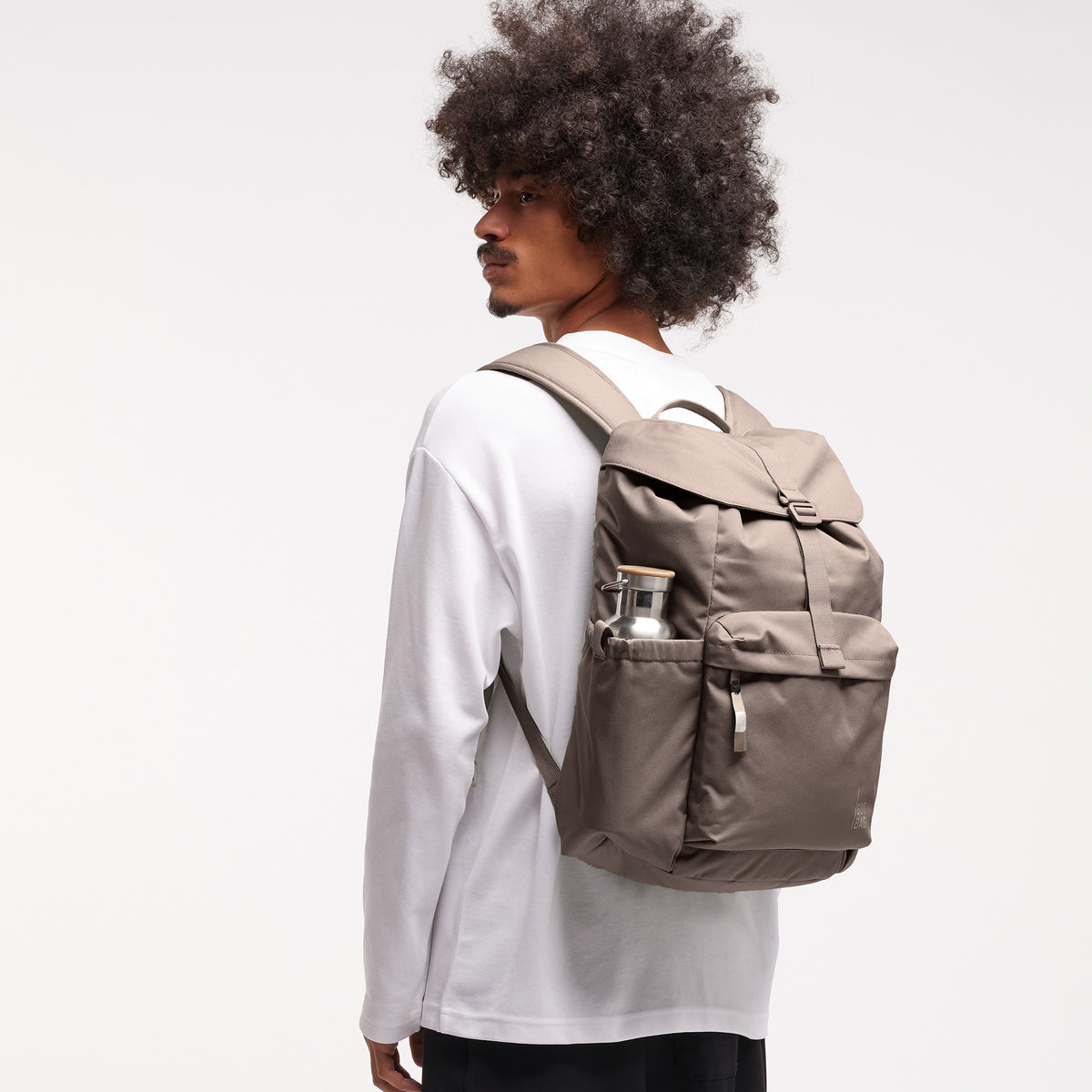 FLAP PACK Rucksack in oyster (klassisches Taupe-Braun) von einem Mann auf dem Rücken getragen.