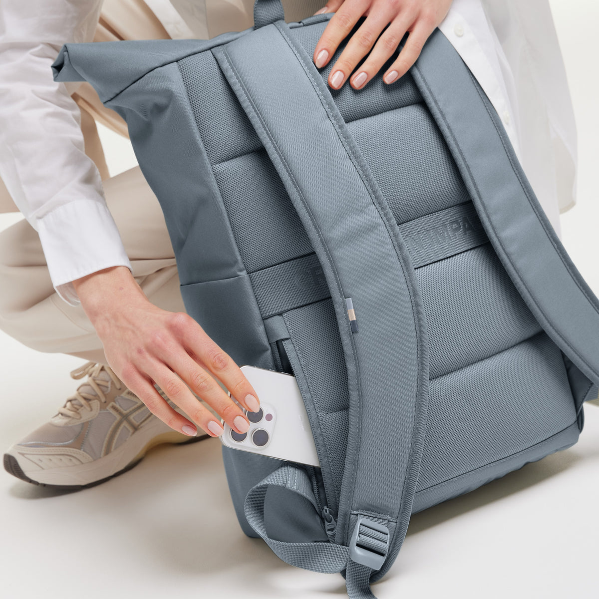 ROLLTOP EASY Rucksack in marlin (grau-blau), eine Frau hält ein Smartphone in einer Seitentasche.