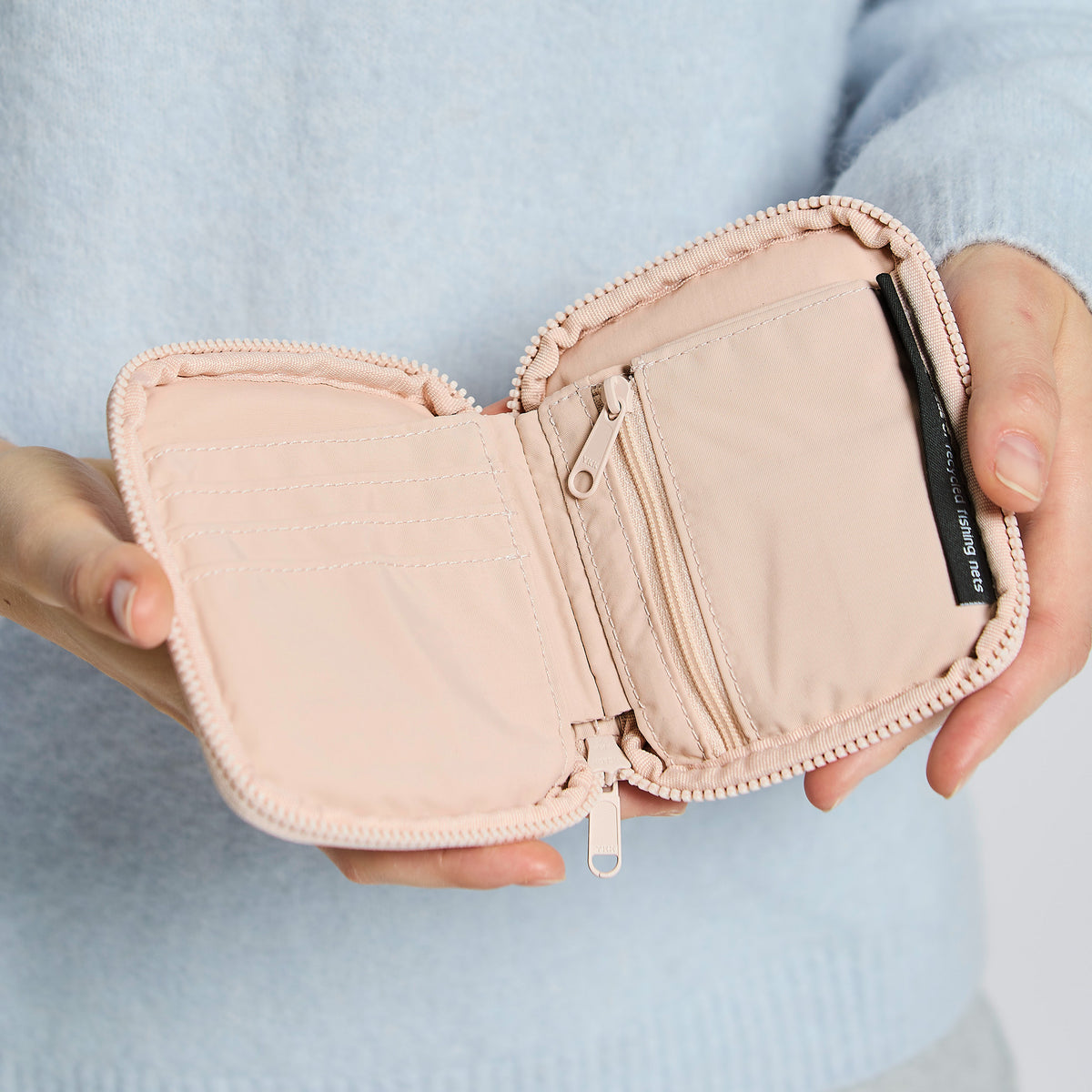 WALLET Accessoire in pearl (helles Puder-Rosa) von einer Frau in der Hand gehalten.