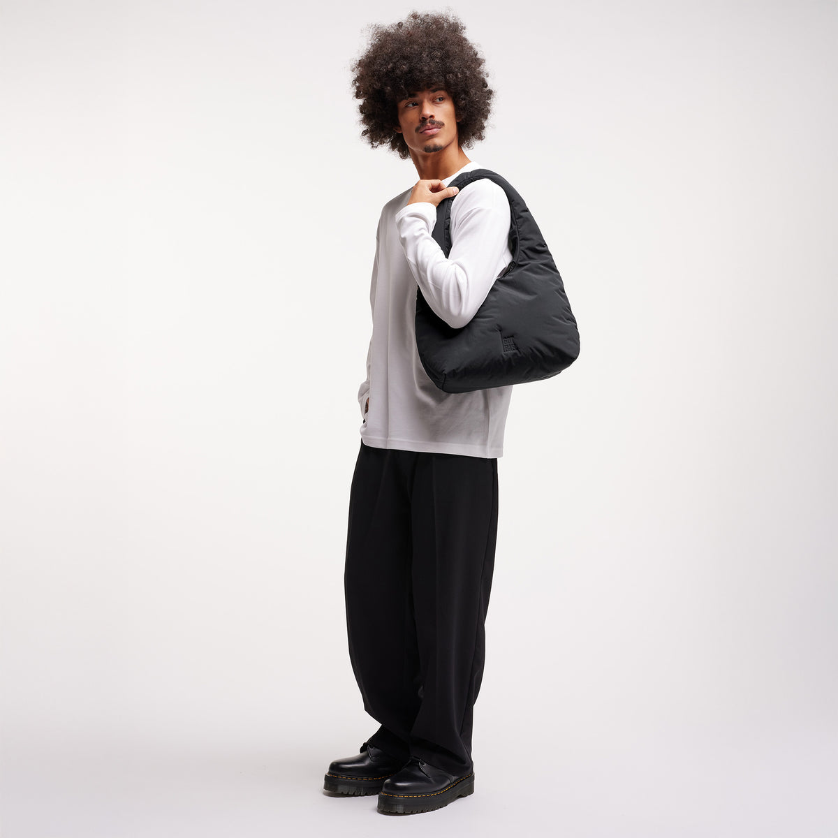 CLOUD SHOULDER Tasche in black (Schwarz) von einem Mann über der Schulter getragen.