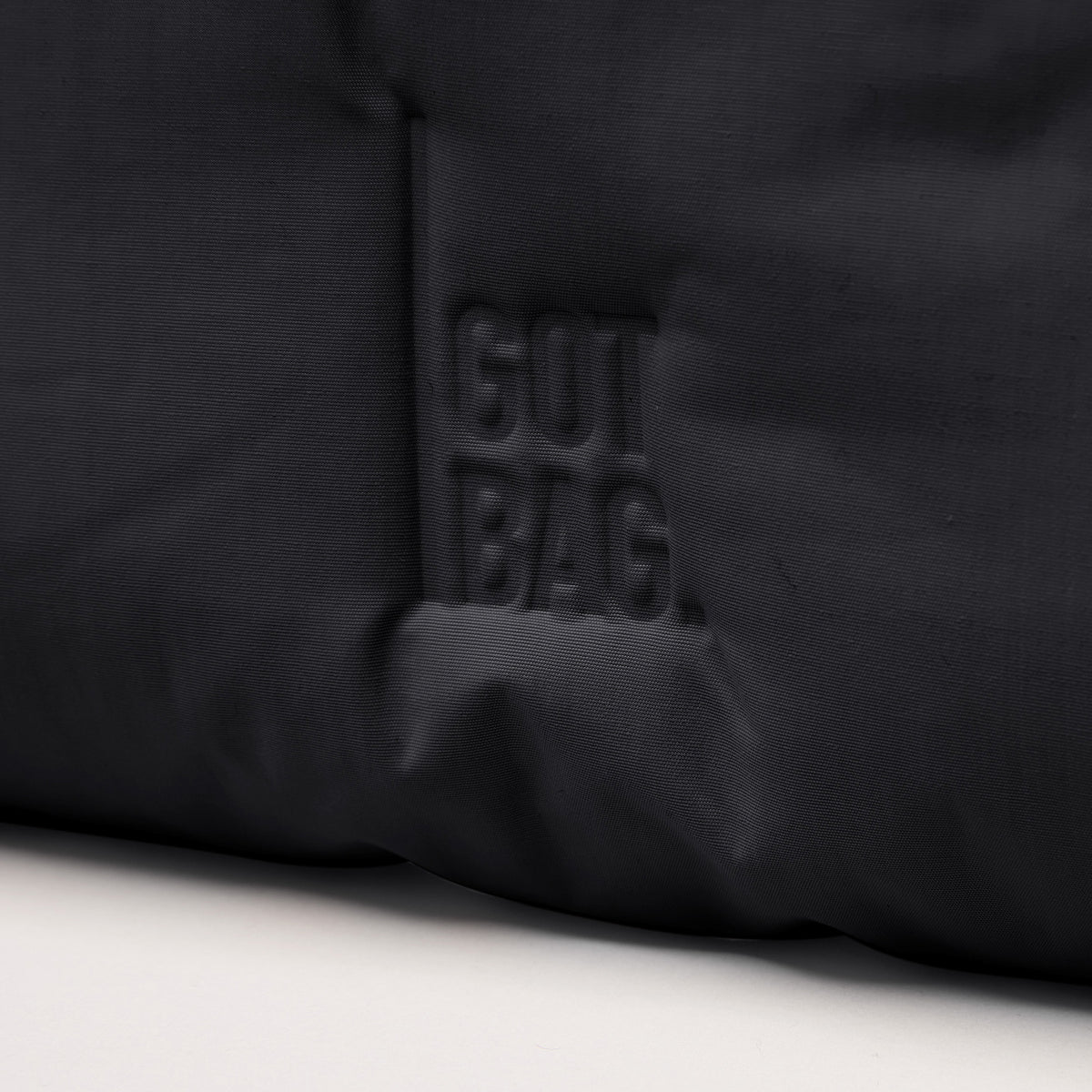 CLOUD SHOULDER Tasche in black (Schwarz) mit geprägtem GUT BAG Logo und Stofftextur als Detailaufnahme.