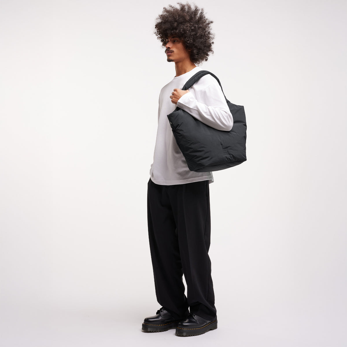 CLOUD TOTE BAG Tasche von einem Mann über der Schulter getragen.